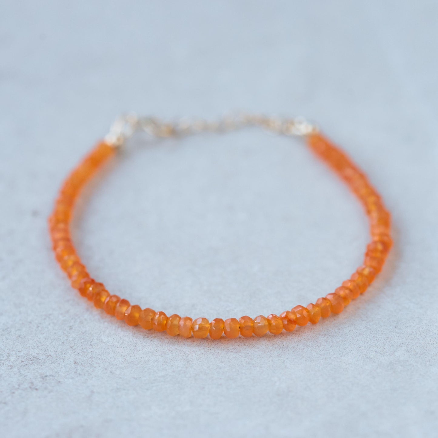 Carnelian bracelet featuring polished orange stones on a 14K gold clasp, showcasing elegant jewelry craftsmanship.
