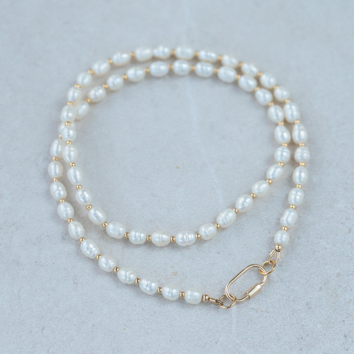 Freshwater pearl necklace with 14K gold clasp from Earthly Abundance, featuring lustrous white pearls on a delicate chain.
