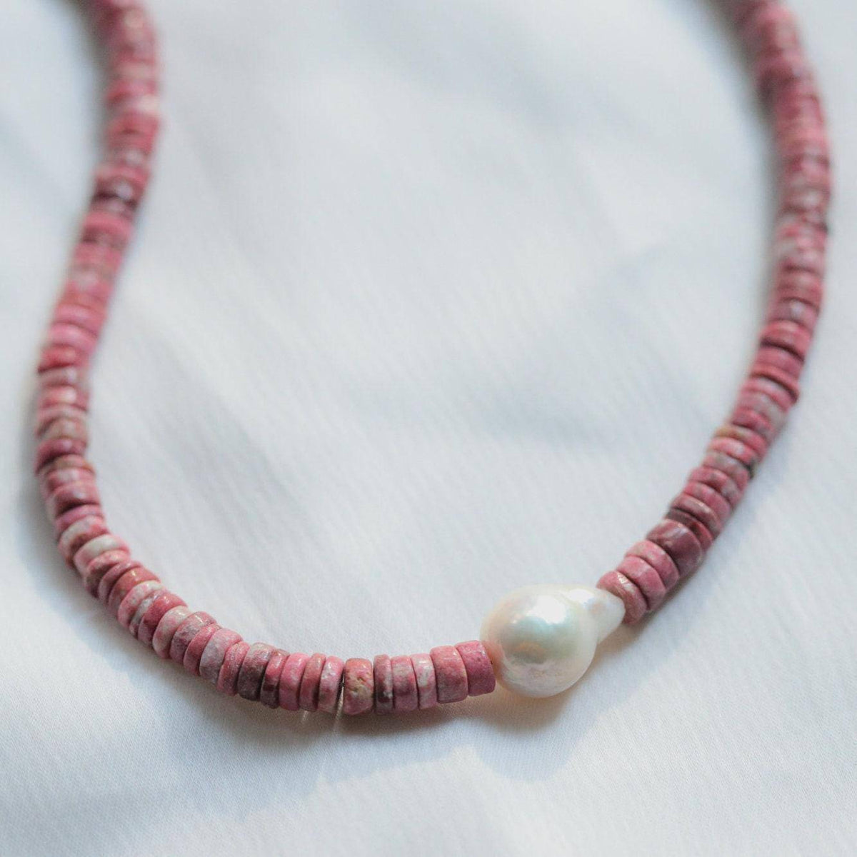 Pink Thulite pearl necklace by Earthly Abundance Jewelry with pink gemstones and delicate clasp on a white background.