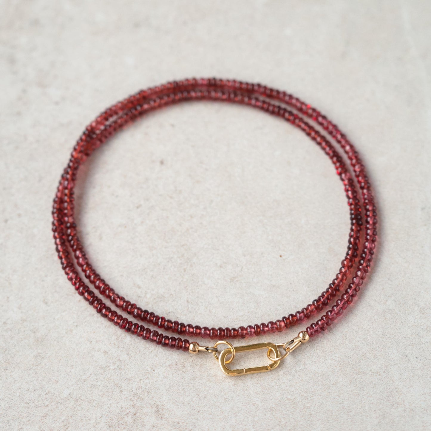 Garnet carabiner necklace by Earthly Abundance featuring a polished garnet stone attached to a metal chain.