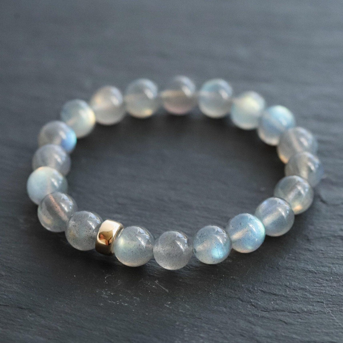 Labradorite bracelet with 9mm beads and 14K gold accents, featuring iridescent labradorite stones on a delicate jewelry strand.