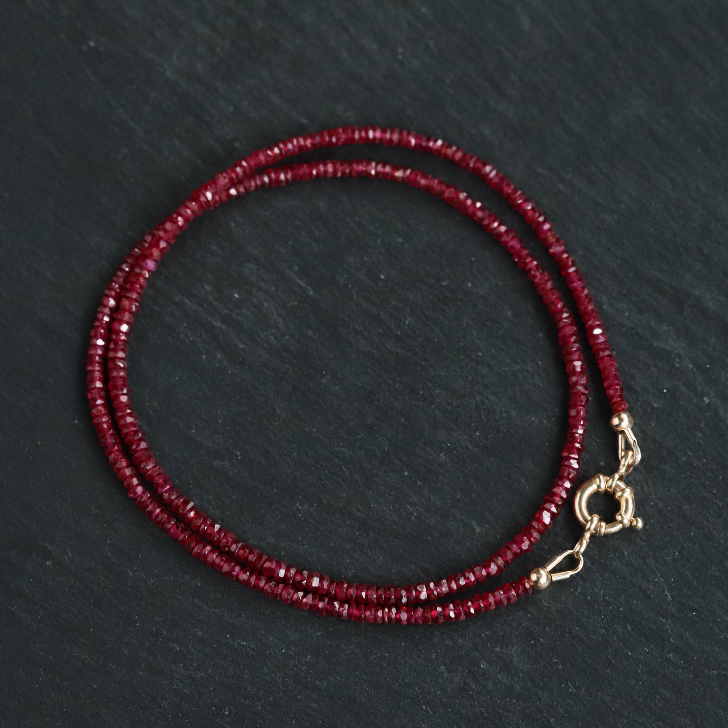 14K Anchor Ruby Necklace by Earthly Abundance featuring a polished gold anchor pendant with a vibrant ruby gemstone.