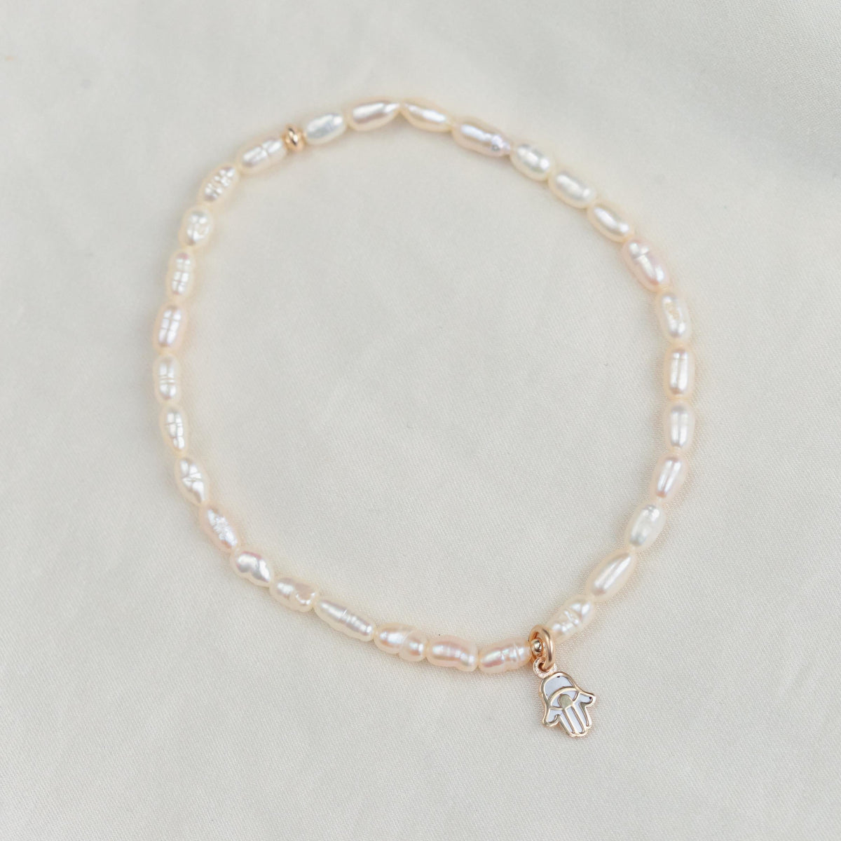 Freshwater pearl bracelet by Earthly Abundance featuring lustrous white pearls and a delicate clasp on a soft background.