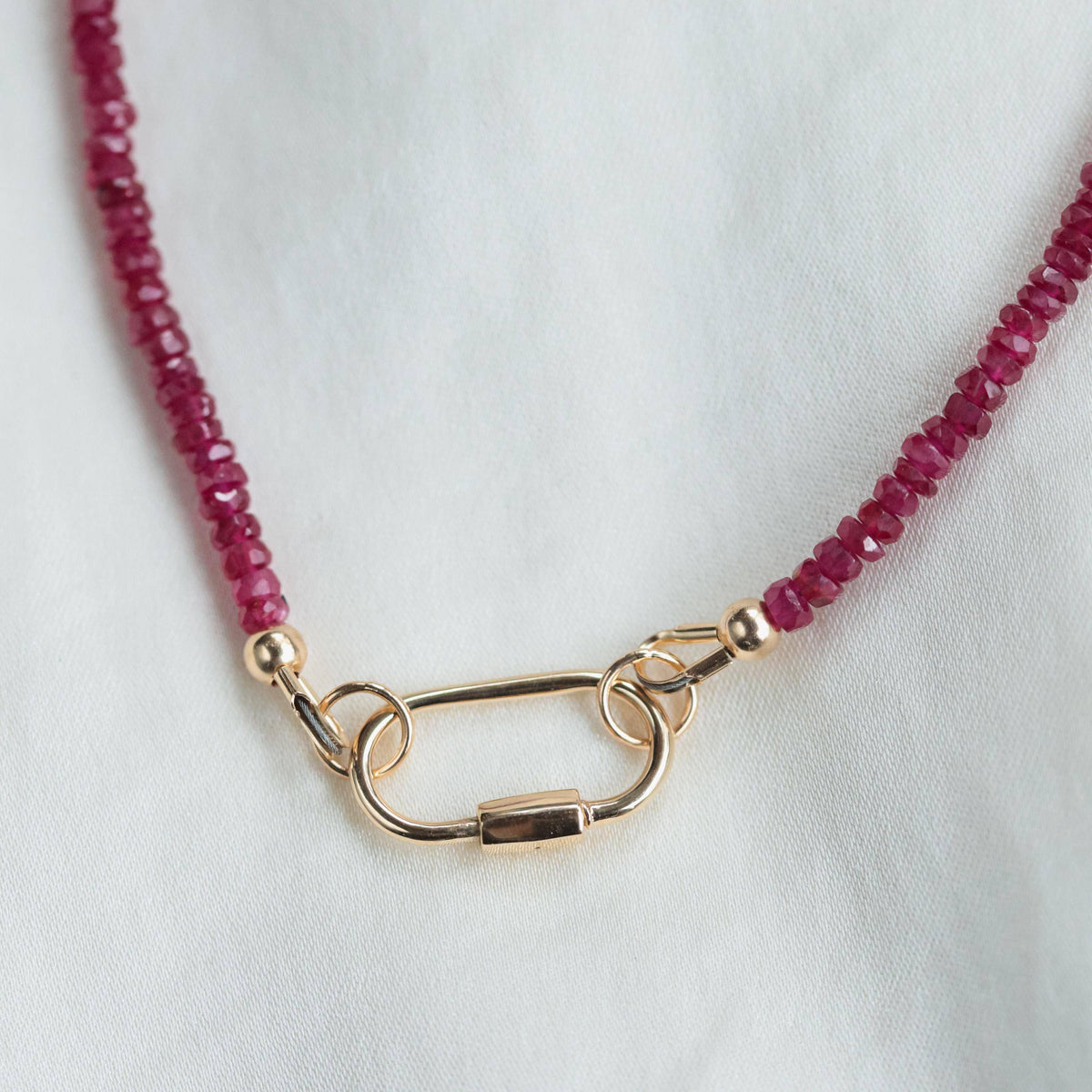 Longido Ruby Carabiner necklace by Earthly Abundance Jewelry featuring a vibrant ruby pendant on a sleek metal chain.