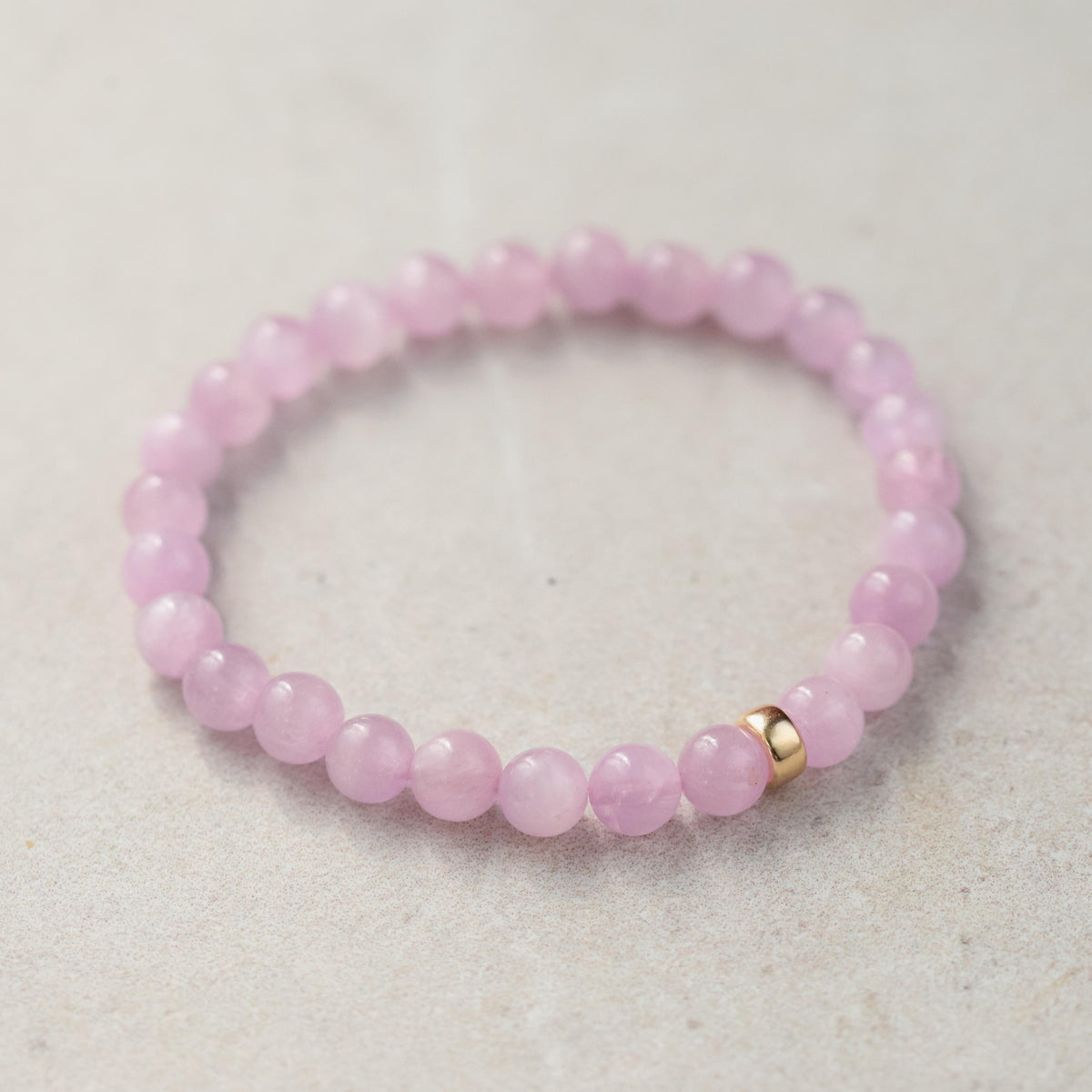 Kunzite bracelet with 7mm beads from Earthly Abundance, featuring pink-purple stones on a stretch cord.