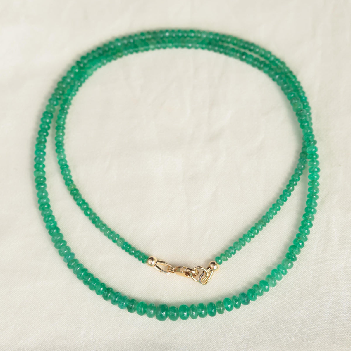 Zambian emerald smooth rondel necklace featuring polished green emerald beads on a delicate string, crafted by Earthly Abundance.