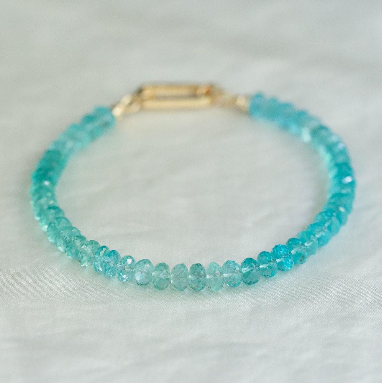 A 14K gold apatite bracelet featuring polished blue-green apatite stones on a delicate gold chain.