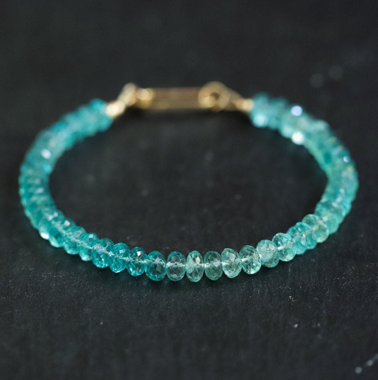 A 14K gold apatite bracelet with polished blue-green stones on a delicate chain, showcasing elegant jewelry craftsmanship.