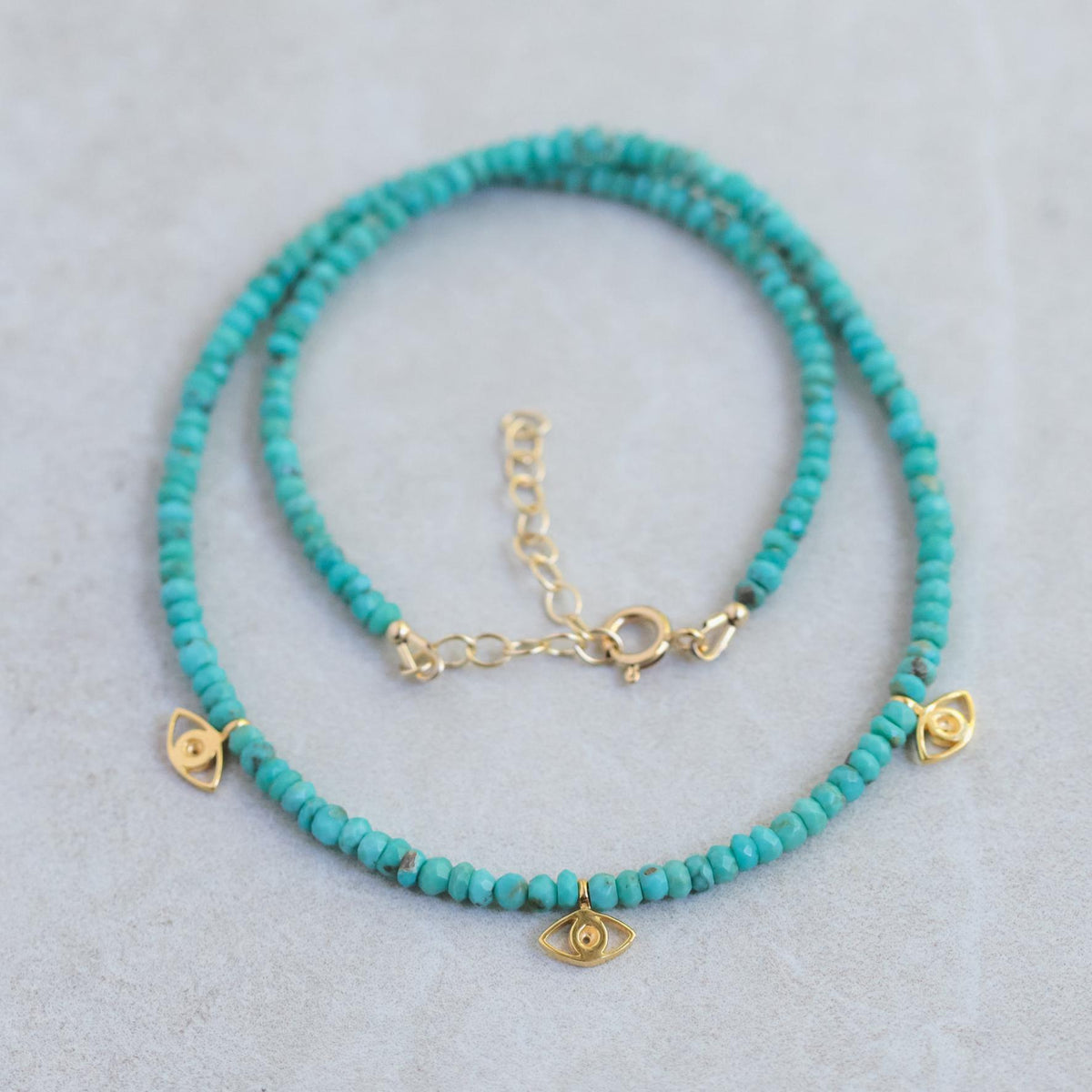 Turquoise evil eye beaded necklace with colorful beads, handcrafted by Earthly Abundance, hanging on a neutral background.