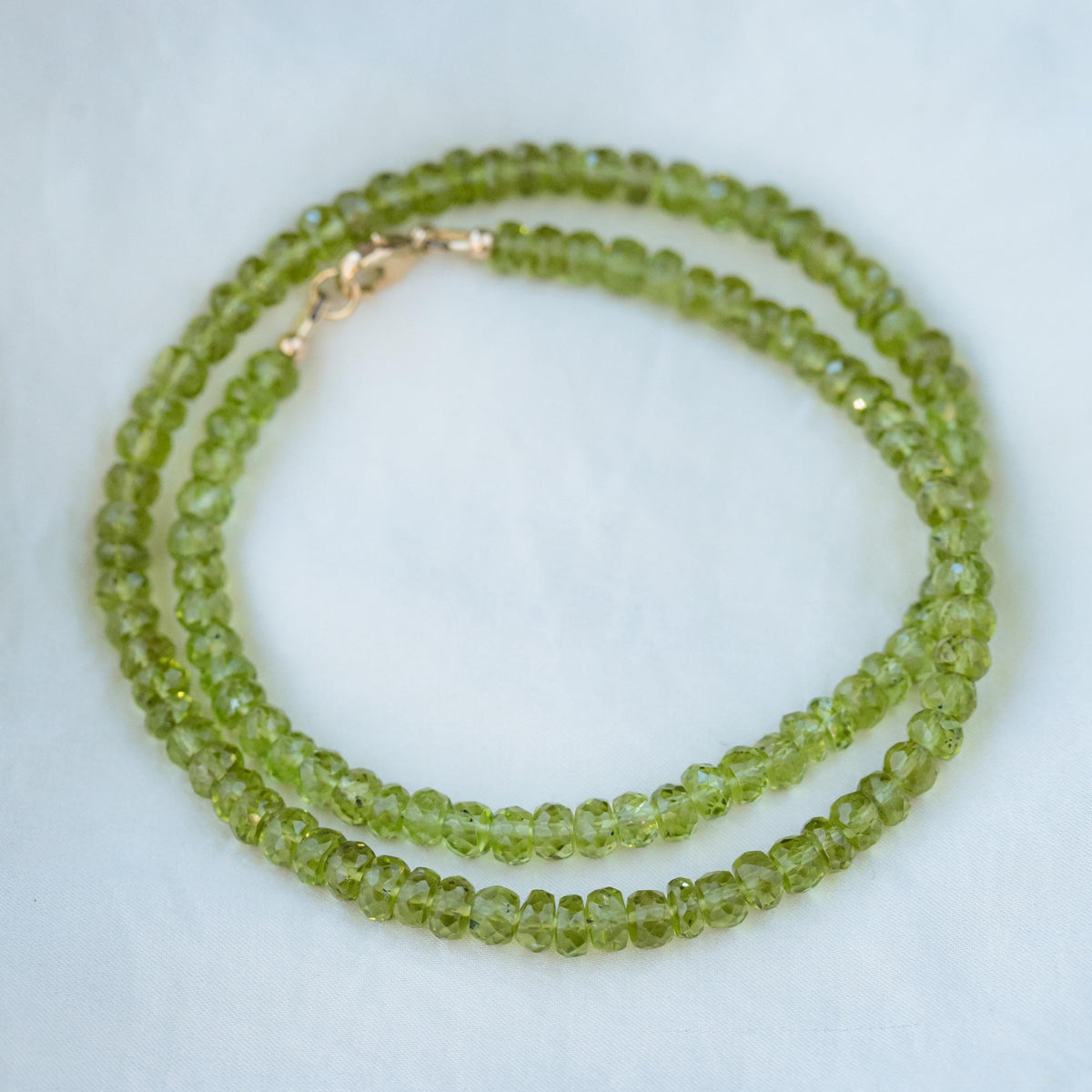 14K Peridot necklace featuring a vibrant green gemstone on a delicate gold chain, by Earthly Abundance.