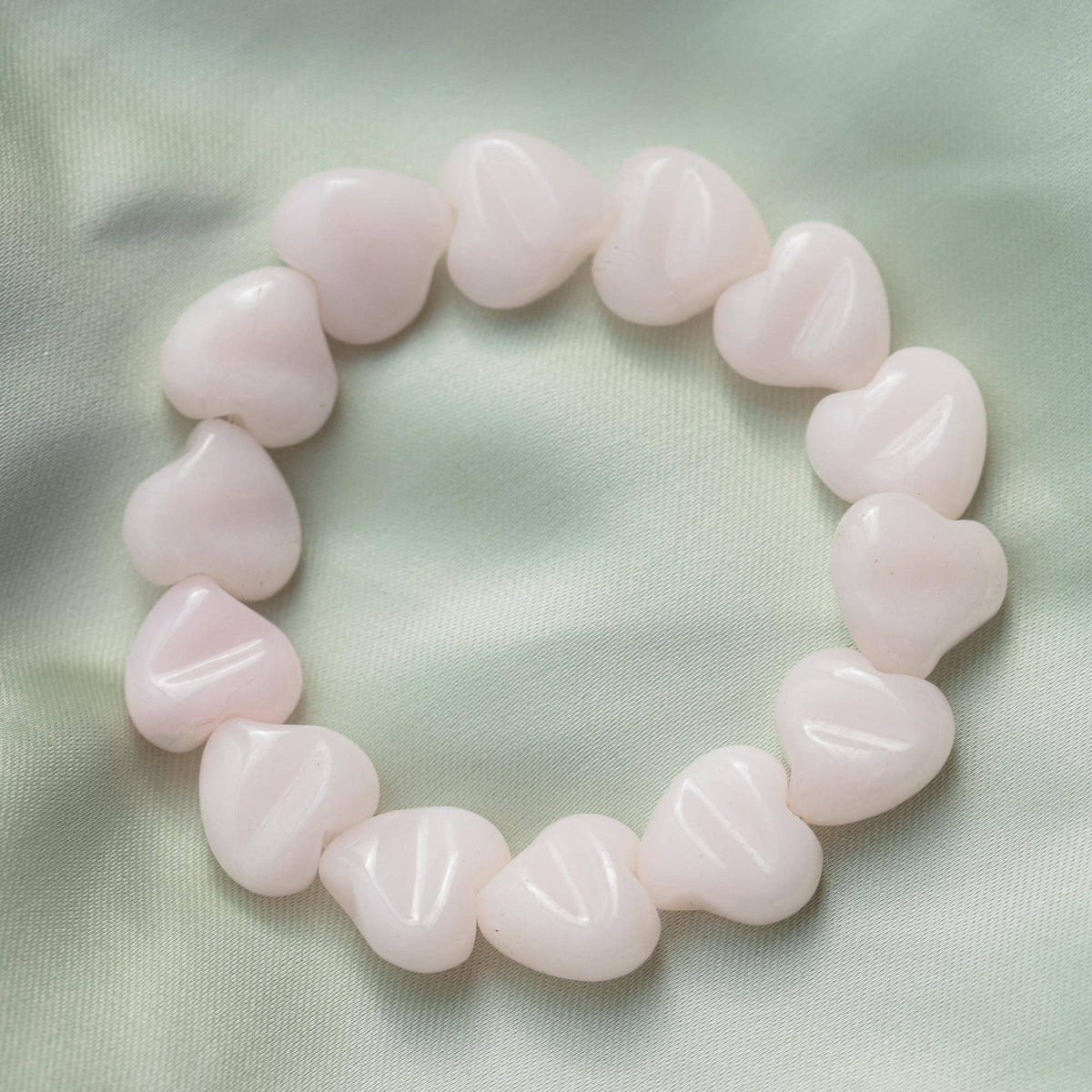 Pink mango calcite heart-shaped bracelet from Earthly Abundance Jewelry featuring polished stones on an elastic band.