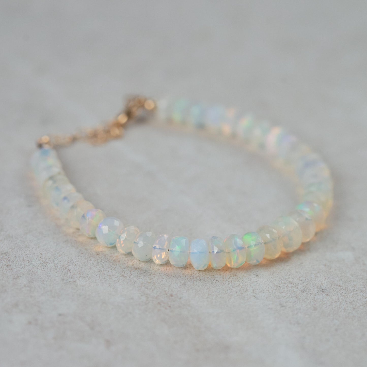 Soft fire opal bracelet in 14K gold setting, featuring vibrant, iridescent gemstones on a delicate bracelet chain.