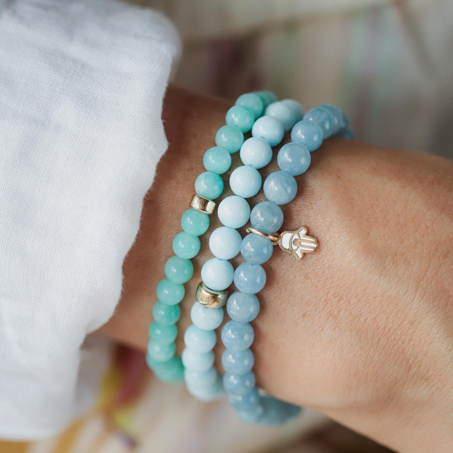 Aquamarine and mother of pearl Hamsa bracelet with intricate design, featuring blue gemstones and silver accents.