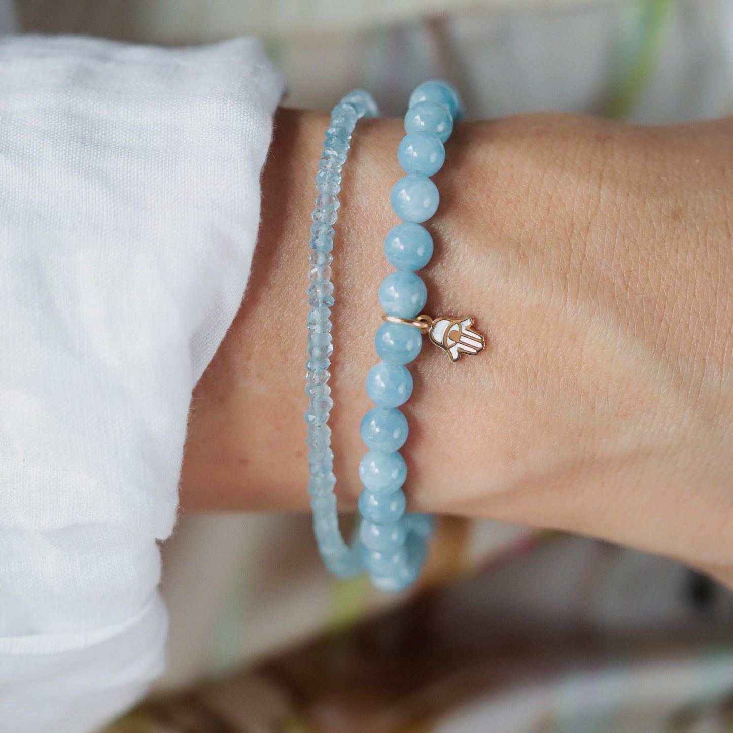 Aquamarine and mother of pearl Hamsa bracelet with intricate design, featuring vibrant blue stones and detailed metalwork.