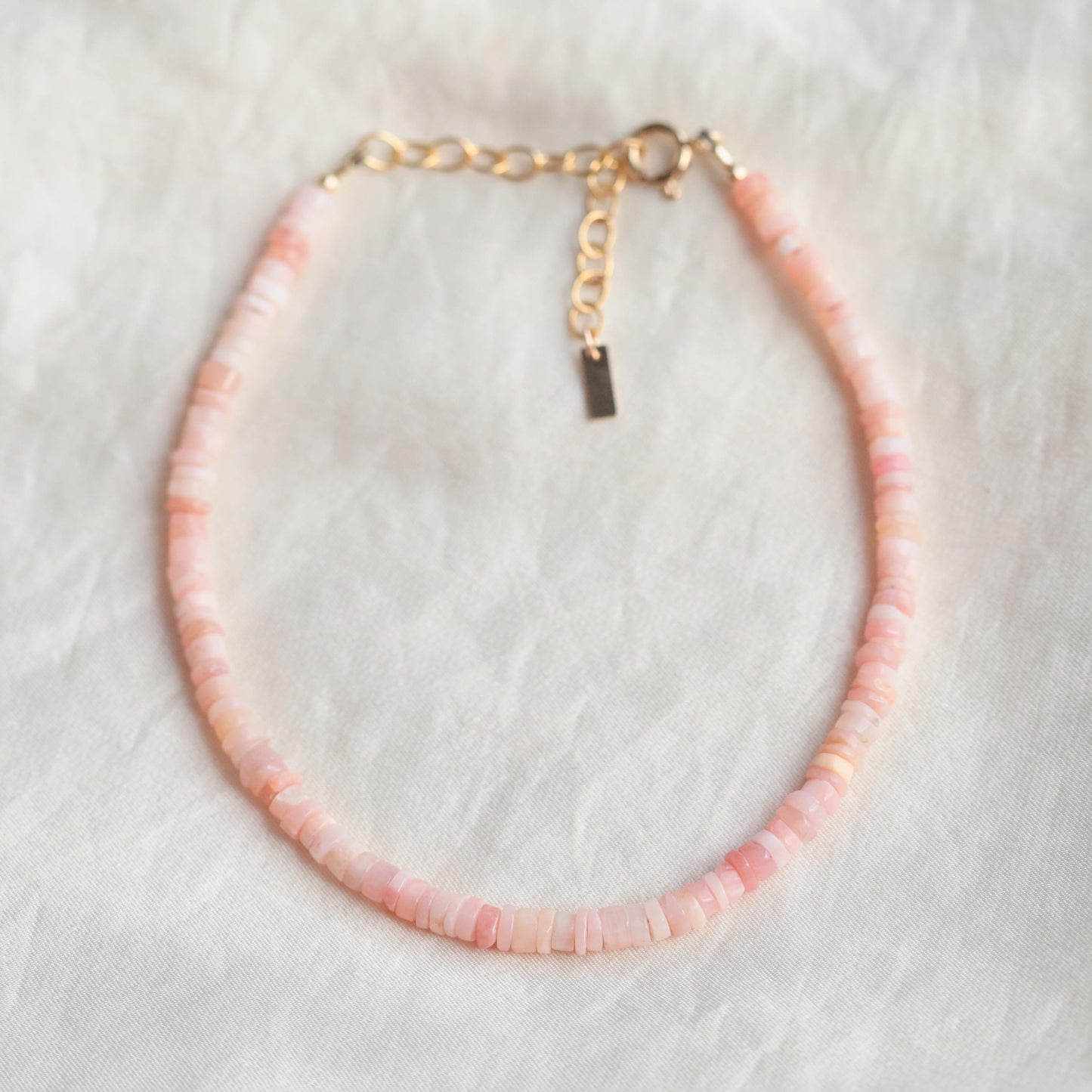 Pink opal heishi anklet featuring small round beads, handmade by Earthly Abundance, on a light background.