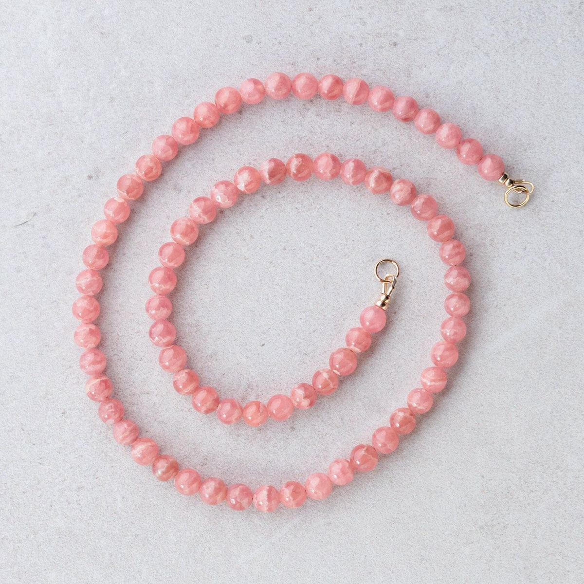 Earthly Abundance AAAA+ Rhodochrosite carabiner necklace featuring a polished pink stone pendant on a silver chain.