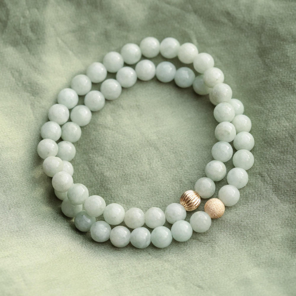 Sixmm jadeite gemstone bead from Earthly Abundance Jewelry, smooth and polished green jadeite, close-up shot.