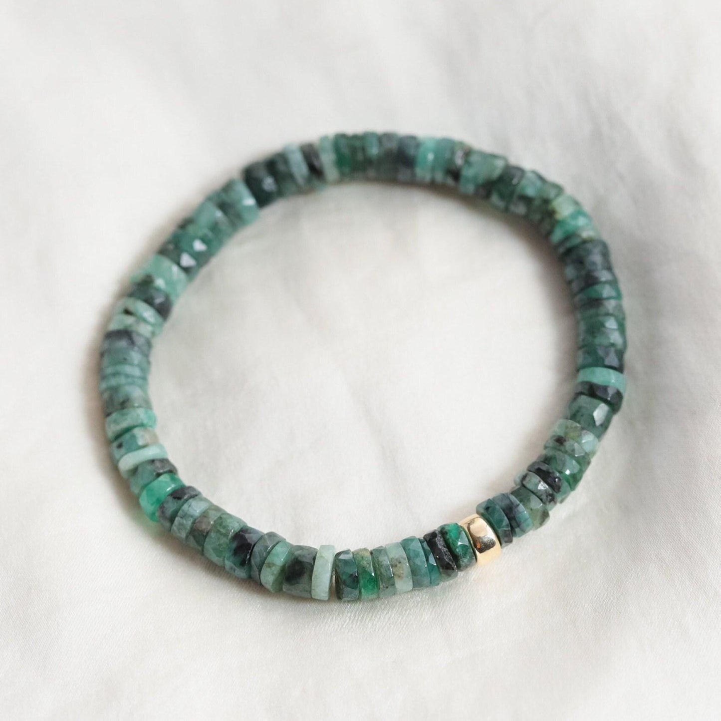 Emerald Heishi bracelet by Earthly Abundance featuring small green gemstone beads strung on an elastic cord.
