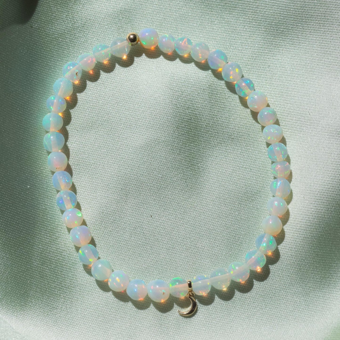 Ethiopian Opal Moon bracelet with 14K gold setting from Earthly Abundance, featuring a moon-shaped opal pendant on a delicate chain