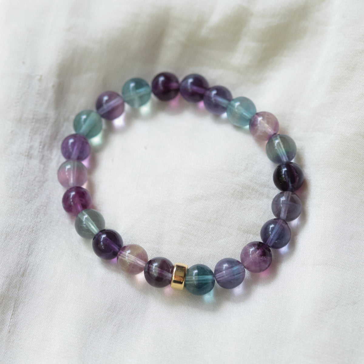 8mm AAAA+ Fluorite bracelet by Earthly Abundance featuring polished green and purple fluorite beads on an elastic band.