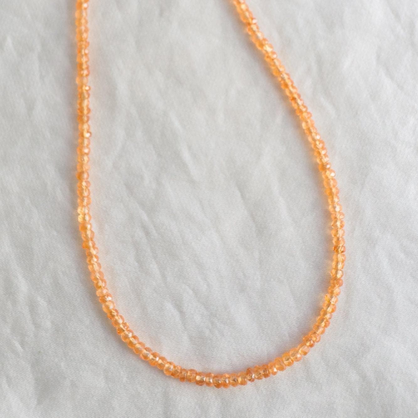 Orange sapphire necklace in 14K gold with a vibrant orange gemstone, featuring a delicate chain and elegant design.