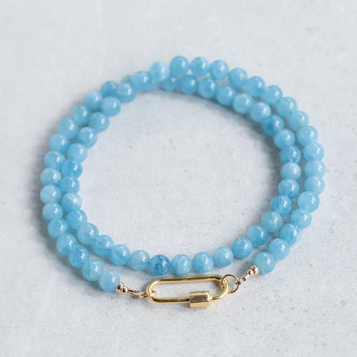 Aquamarine Carabiner Necklace by Earthly Abundance featuring a silver-tone metal carabiner and a vibrant aquamarine gemstone pendant.