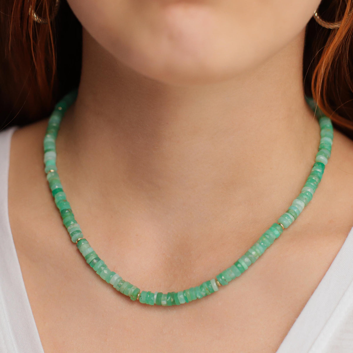 Chrysoprase Heishi necklace with small green gemstone beads from Earthly Abundance, arranged in a layered jewelry display.