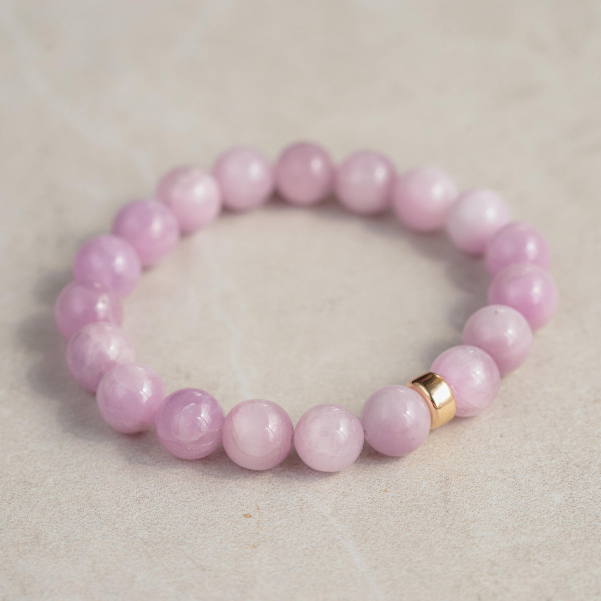 Kunzite bracelet featuring 10mm pink gemstones from Earthly Abundance Jewelry, showcased on a neutral background.
