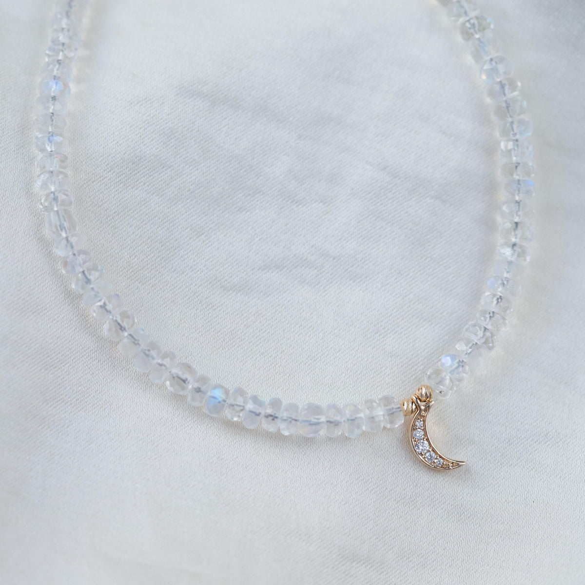 14K diamond moonstone necklace featuring a polished round moonstone pendant with diamond accents, displayed on a delicate chain.