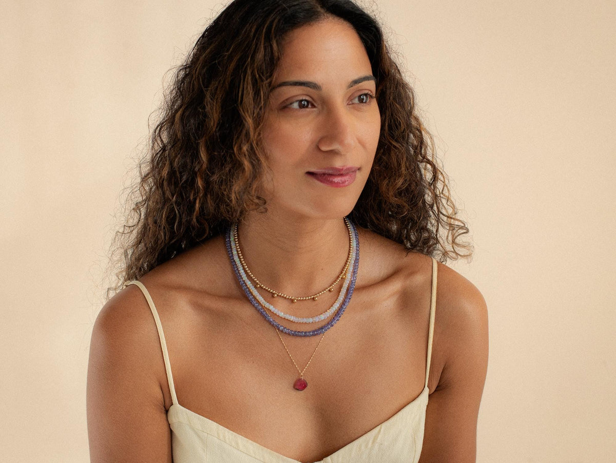 Earthly Abundance Tanzanite smooth rondel necklace with 14K gold clasp, showcasing vibrant blue-purple tanzanite beads on a delicate chain.