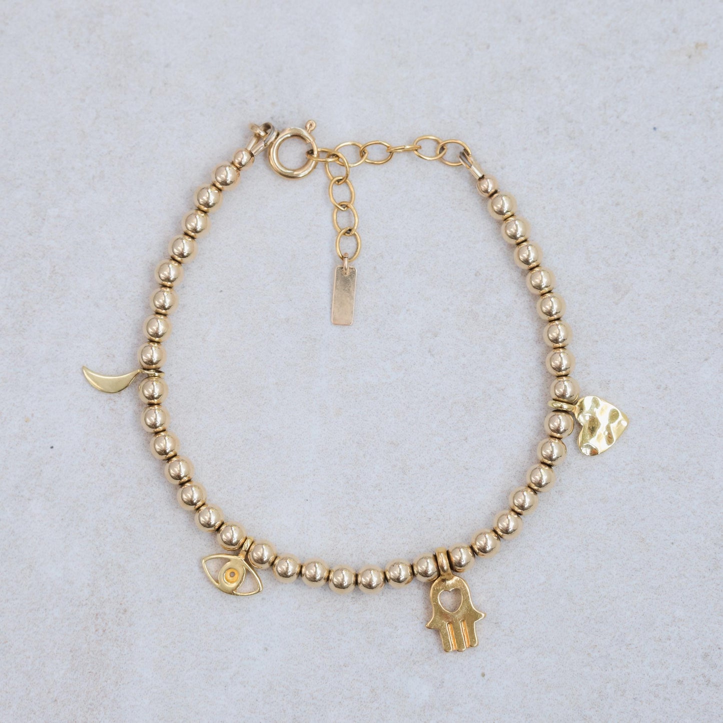 Gold beaded charm bracelet with 4mm beads from Earthly Abundance, featuring small decorative charms on a delicate chain.