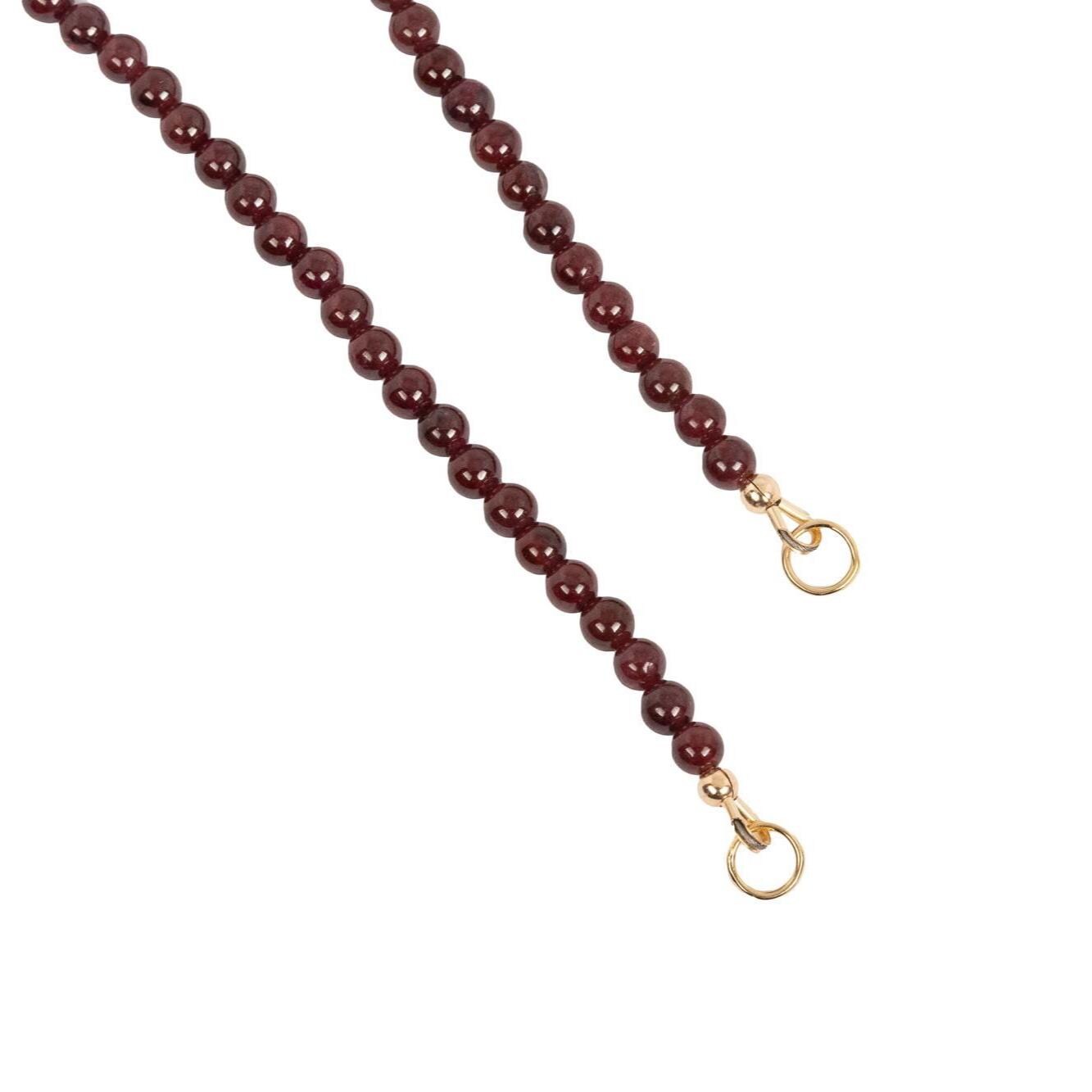 Earthly Abundance garnet carabiner necklace featuring a deep red garnet stone on a silver-tone chain.