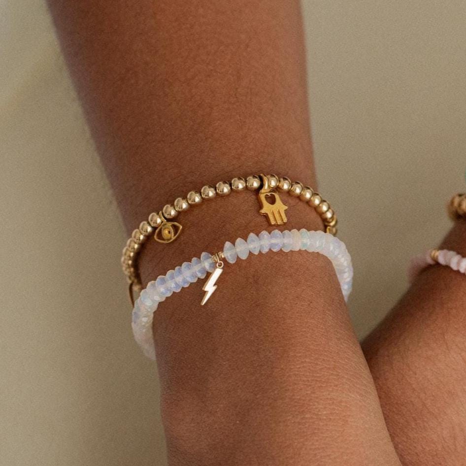 Gold beaded charm bracelet with 4mm beads from Earthly Abundance, featuring decorative charms on a delicate bracelet chain.