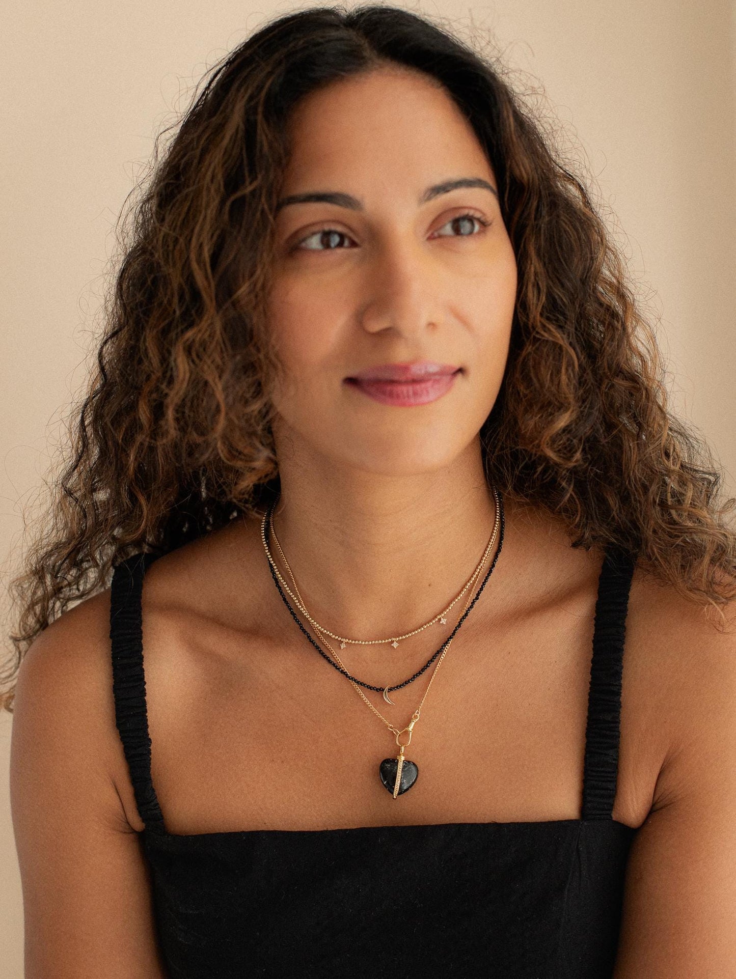 Black spinel moon necklace with 14K gold chain from Earthly Abundance, featuring a polished black spinel moon pendant.