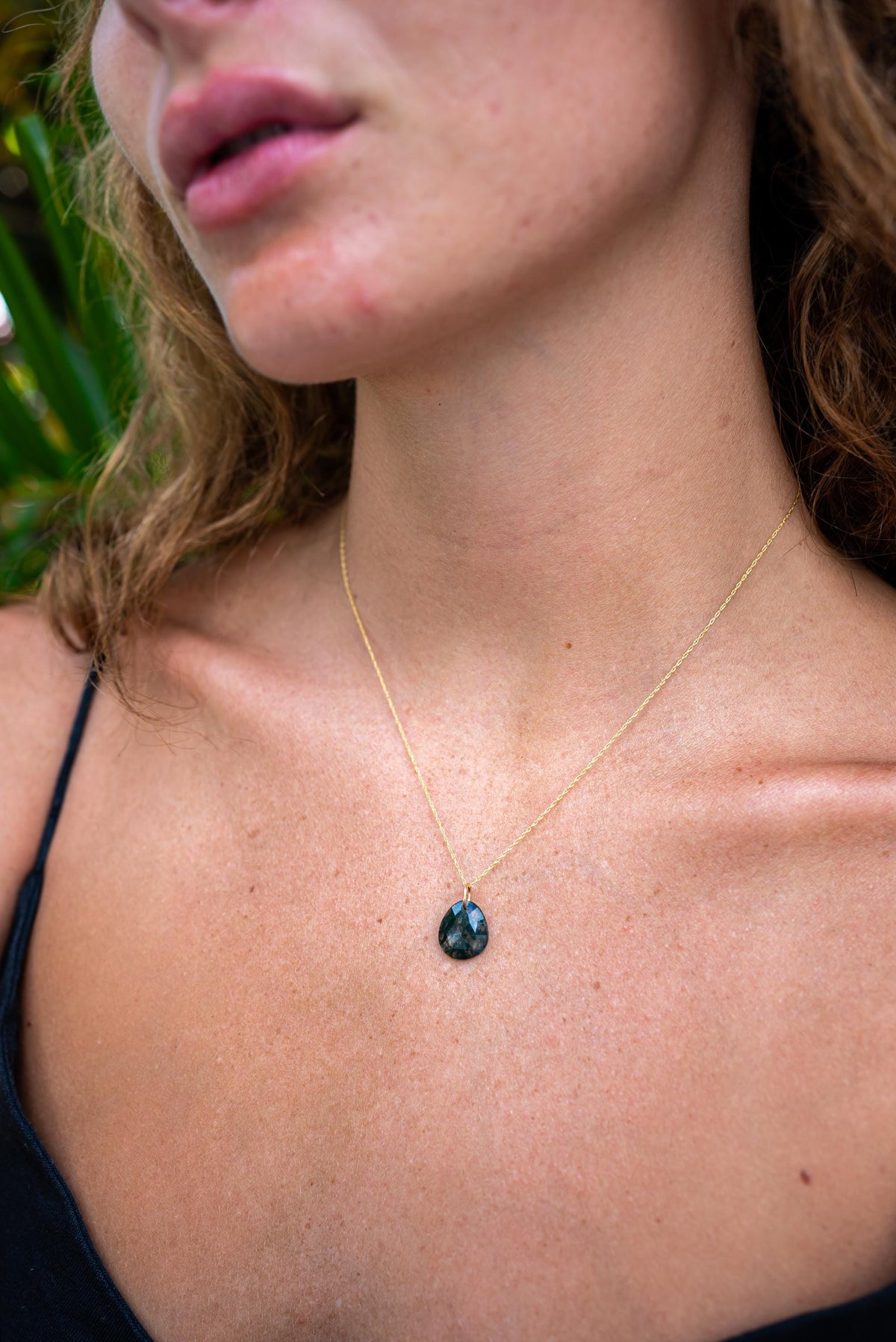 Moss agate pendant from Earthly Abundance showing a polished, natural stone with green and brown moss-like patterns.
