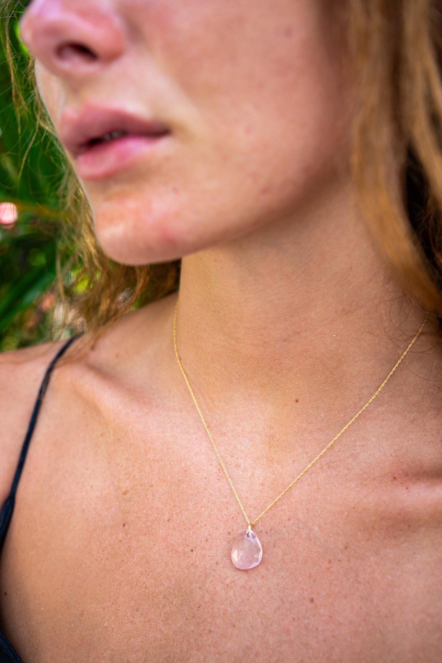 Rose quartz pendant necklace in 14K gold setting, featuring a smooth, polished stone on a delicate chain with subtle gold accents.