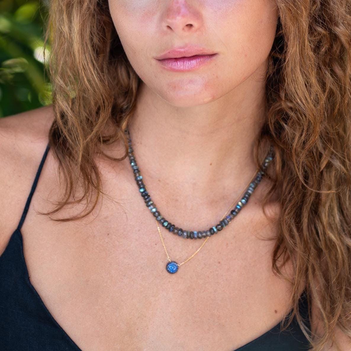 Evil eye labradorite pendant necklace with intricate design, featuring a glowing labradorite stone and protective evil eye charm.
