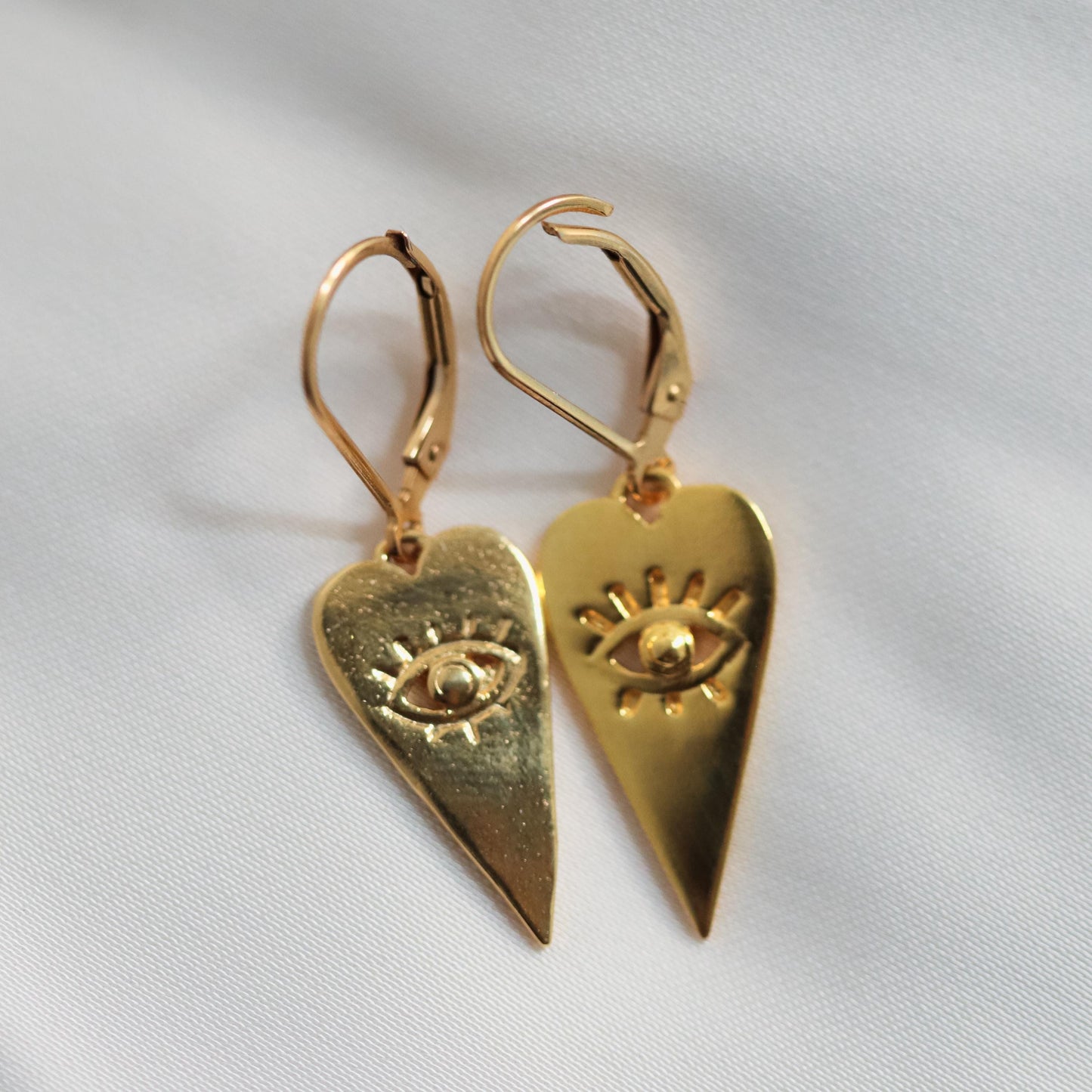 Evil Eye Heart Earrings by Earthly Abundance featuring silver-tone hearts with blue and white evil eye charms.