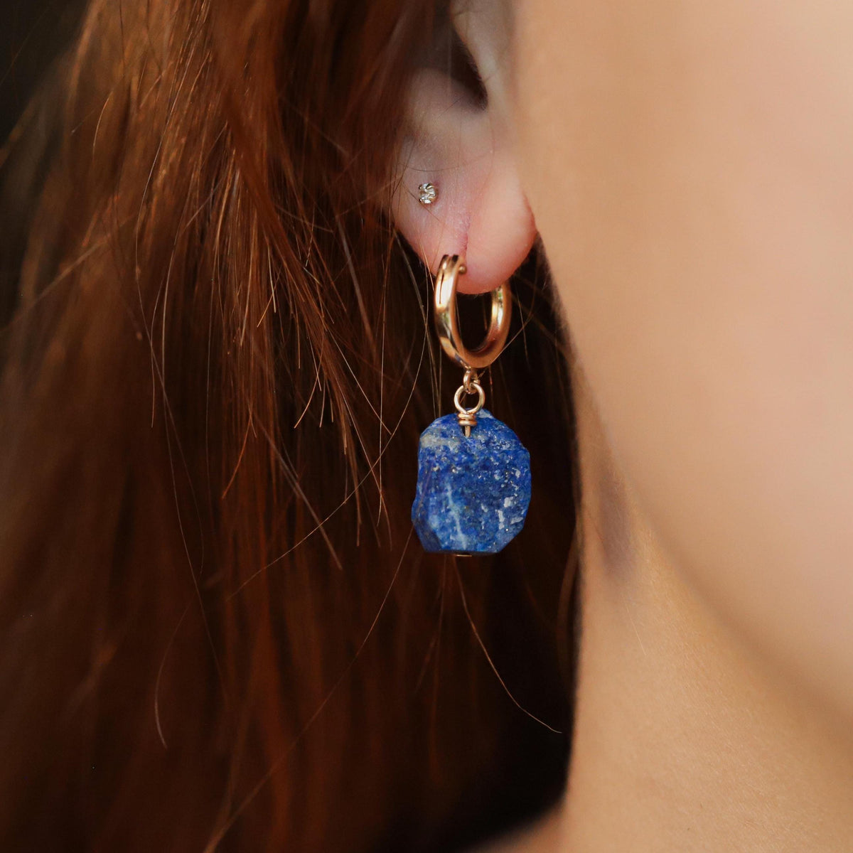Raw Lapis Lazuli huggie earrings by Earthly Abundance featuring natural blue gemstones with gold-tone accents.