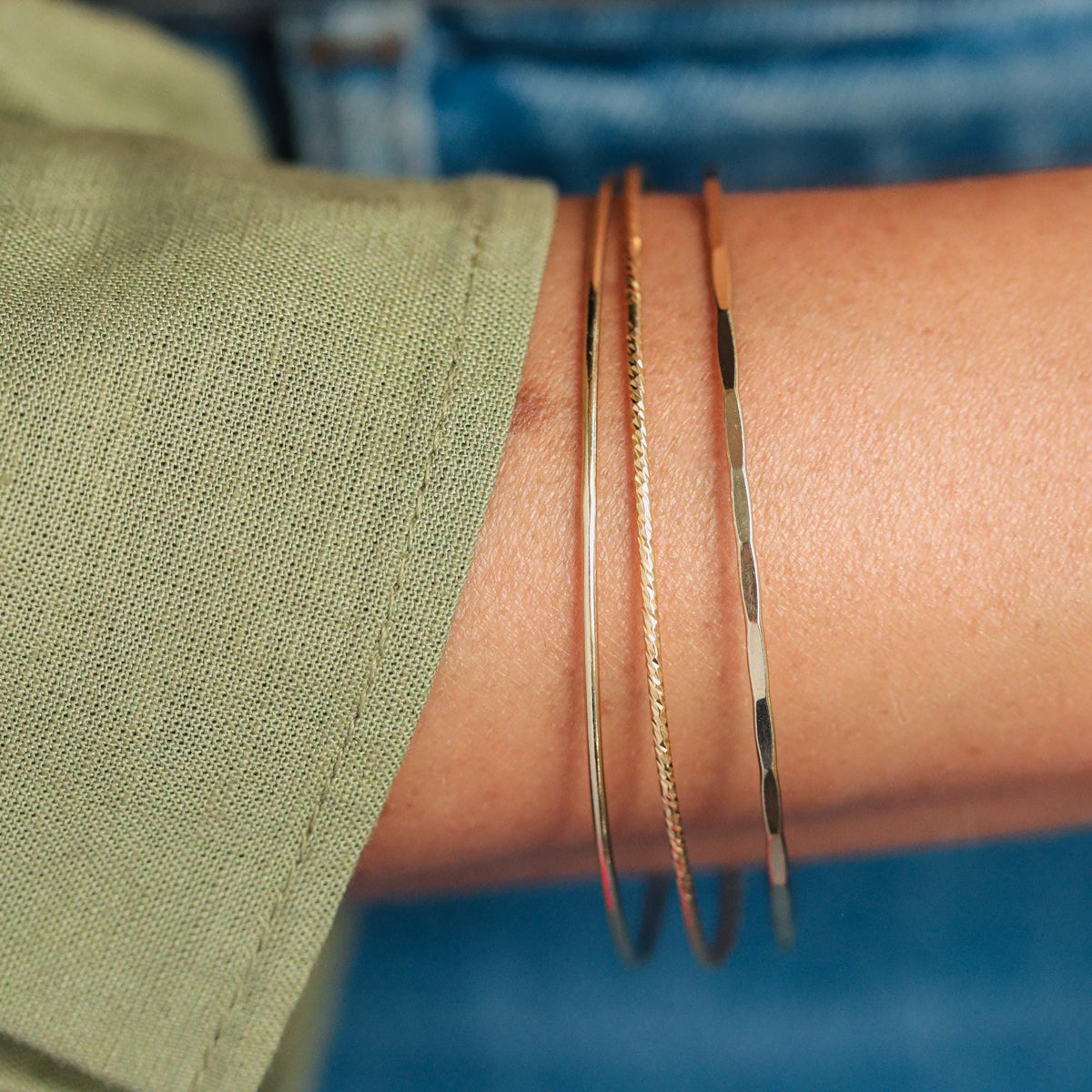 Set of gold filled bangles with smooth, hammered, and sparkly finishes by Earthly Abundance, displayed in a close-up image.