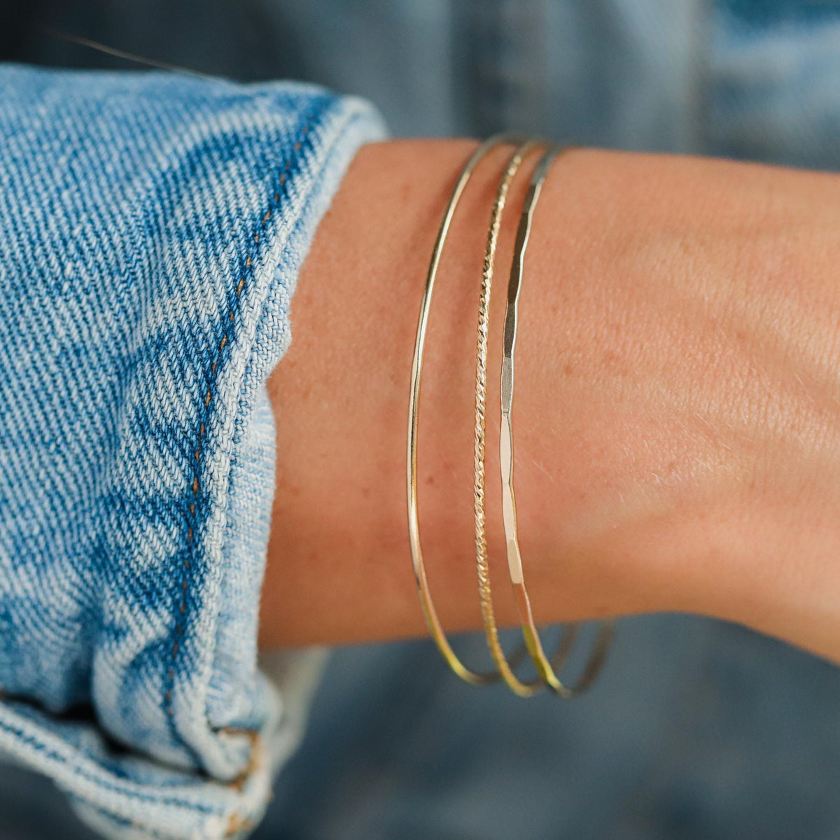 Gold filled bangles set with smooth, hammered, and sparkly finishes, featuring Earthly Abundance jewelry on a white background.