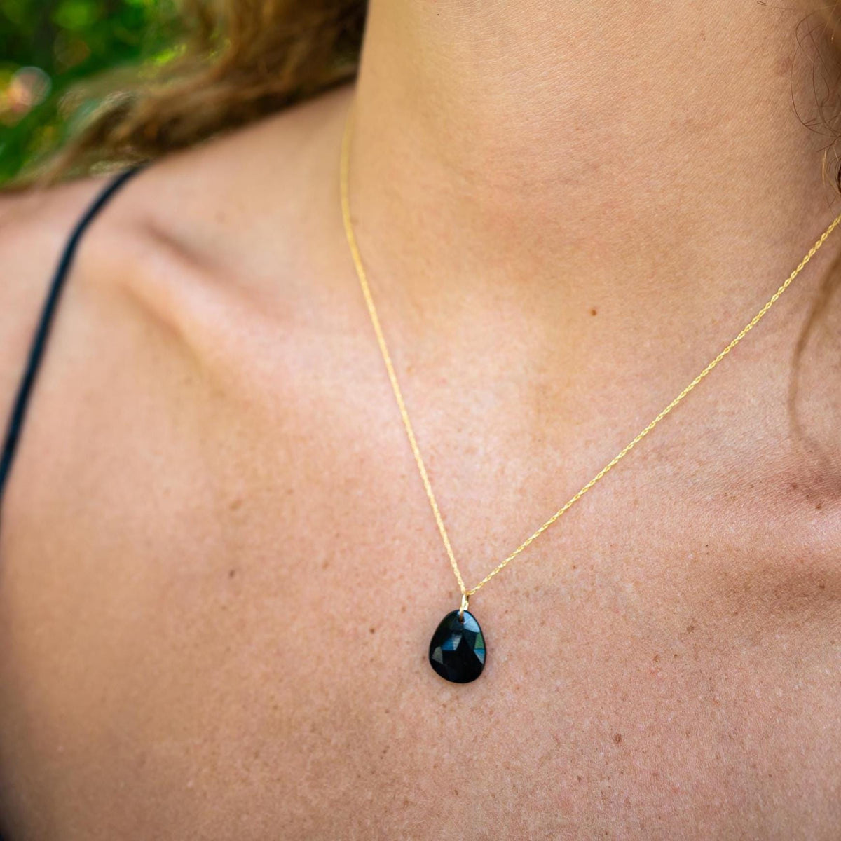 Black Onyx pendant necklace with 14K gold setting from Earthly Abundance, showcasing a polished black gemstone on a delicate chain.