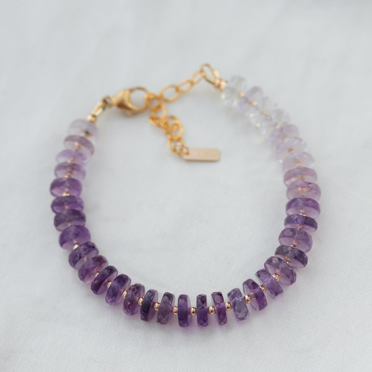 Earthly Abundance Amethyst Heishi Ombre bracelet with purple and lavender beads, showcasing a stylish, layered jewelry design.