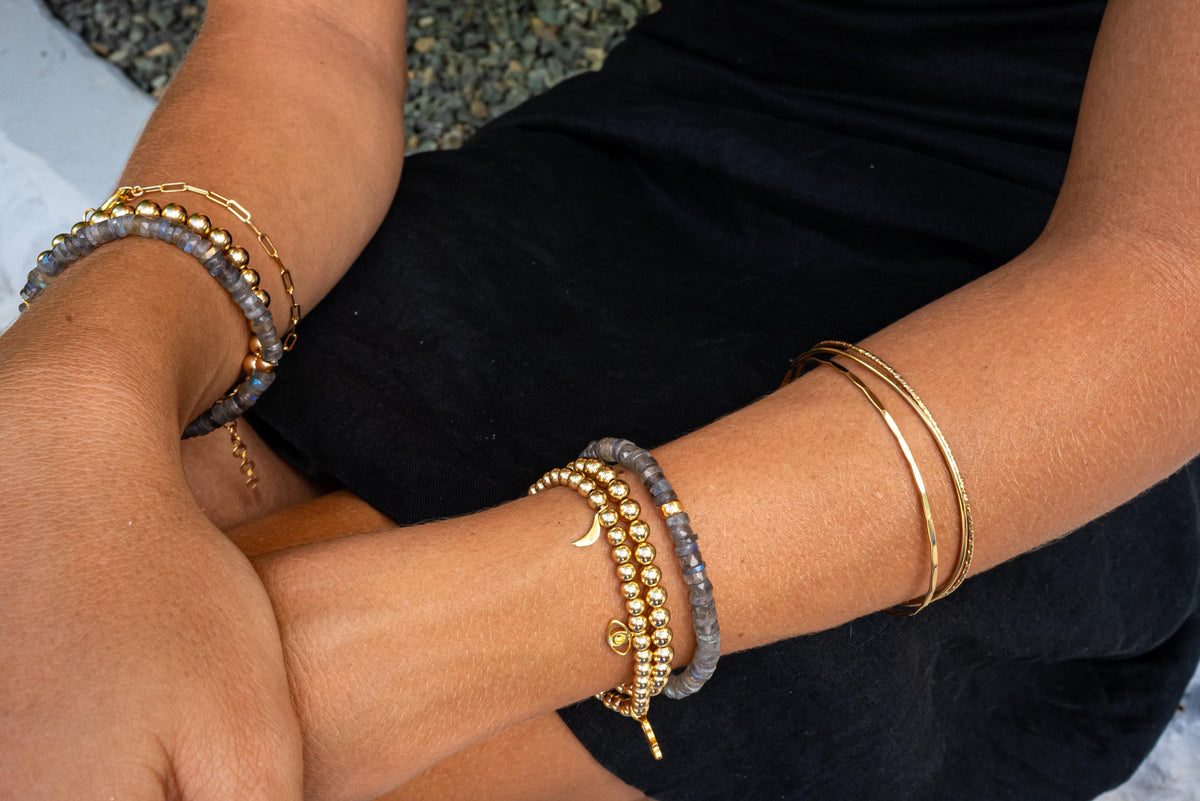Gold beaded charm bracelet with 4mm beads from Earthly Abundance, featuring small decorative charms and a clasp closure.