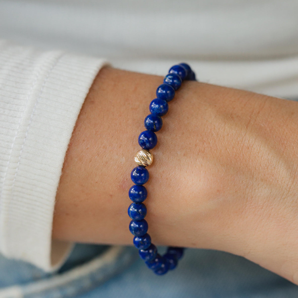 Lapis Lazuli bracelet with 14K gold accents by Earthly Abundance, featuring deep blue stones and gold details on a neutral background.
