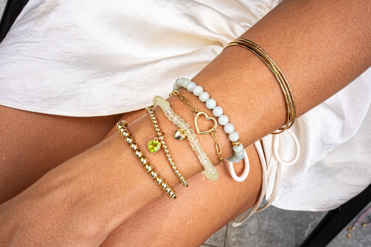 Green Prehnite heart bracelet featuring polished stones from Earthly Abundance displayed on a neutral background.