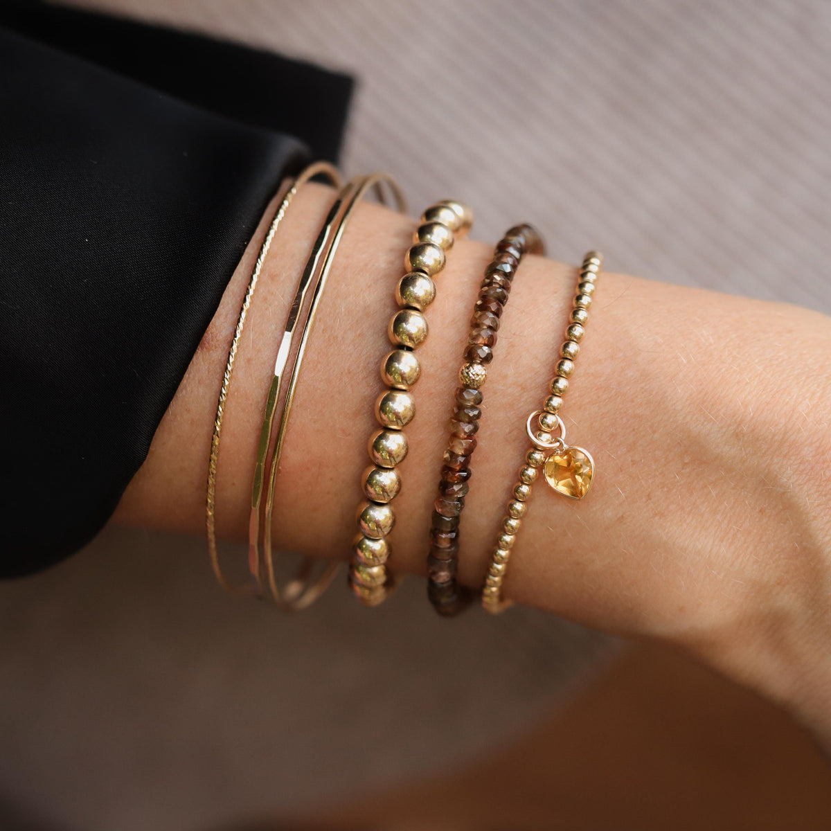 Gold filled bracelet with 14K citrine heart charm, featuring elegant jewelry design and sparkling gemstone detail.