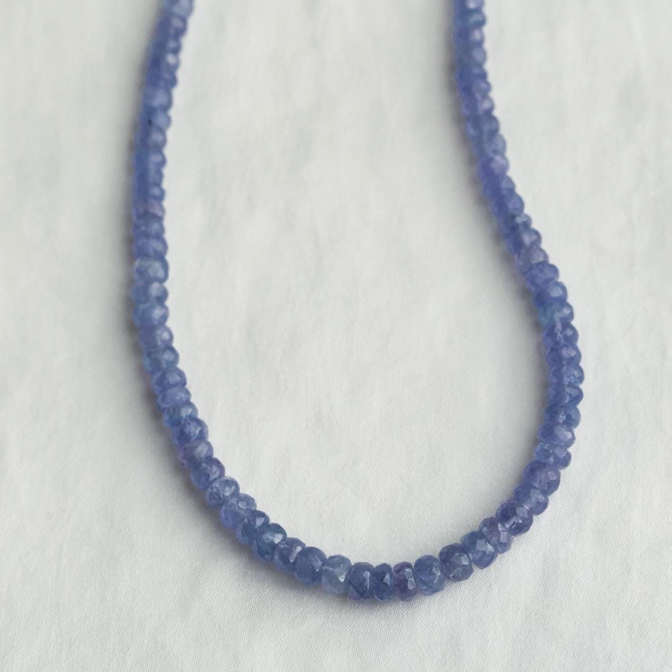 Indigo Muse Tanzanite Necklace featuring deep blue and violet tanzanite gemstones on a silver chain, by Earthly Abundance Jewelry.