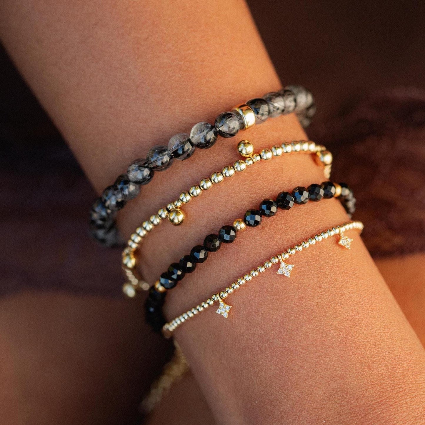 Black spinel bracelet with 14K gold-filled chain from Earthly Abundance, featuring polished black gemstones on a delicate gold bracelet.
