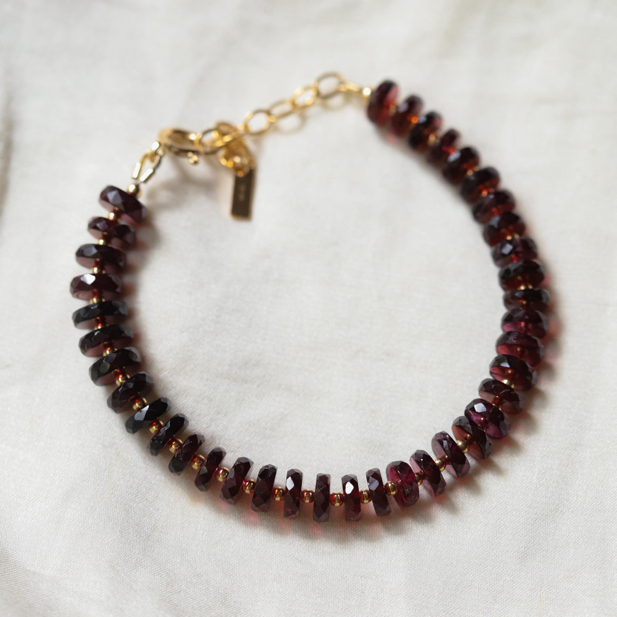 Earthly Abundance garnet stacking bracelet with 14K gold-filled beads and adjustable design, showcasing vibrant red gemstones.